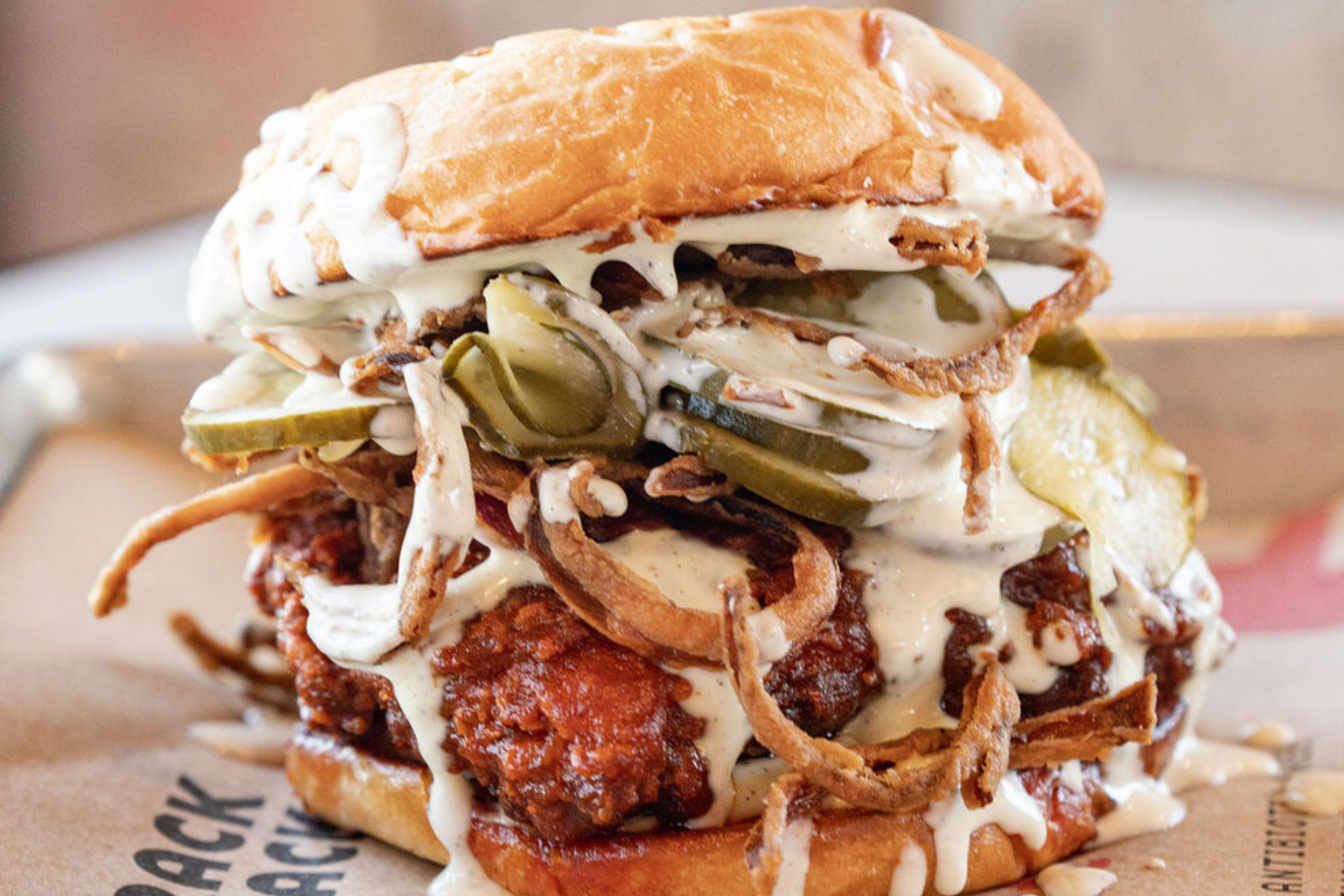 Chicken sandwich with pickles and onions on a tray