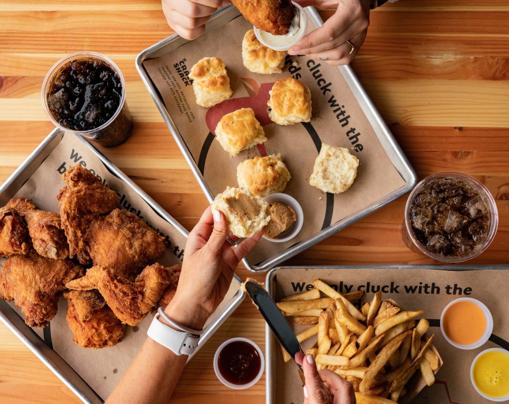 Overhead shot of spread of food on tray and hands reaching out
