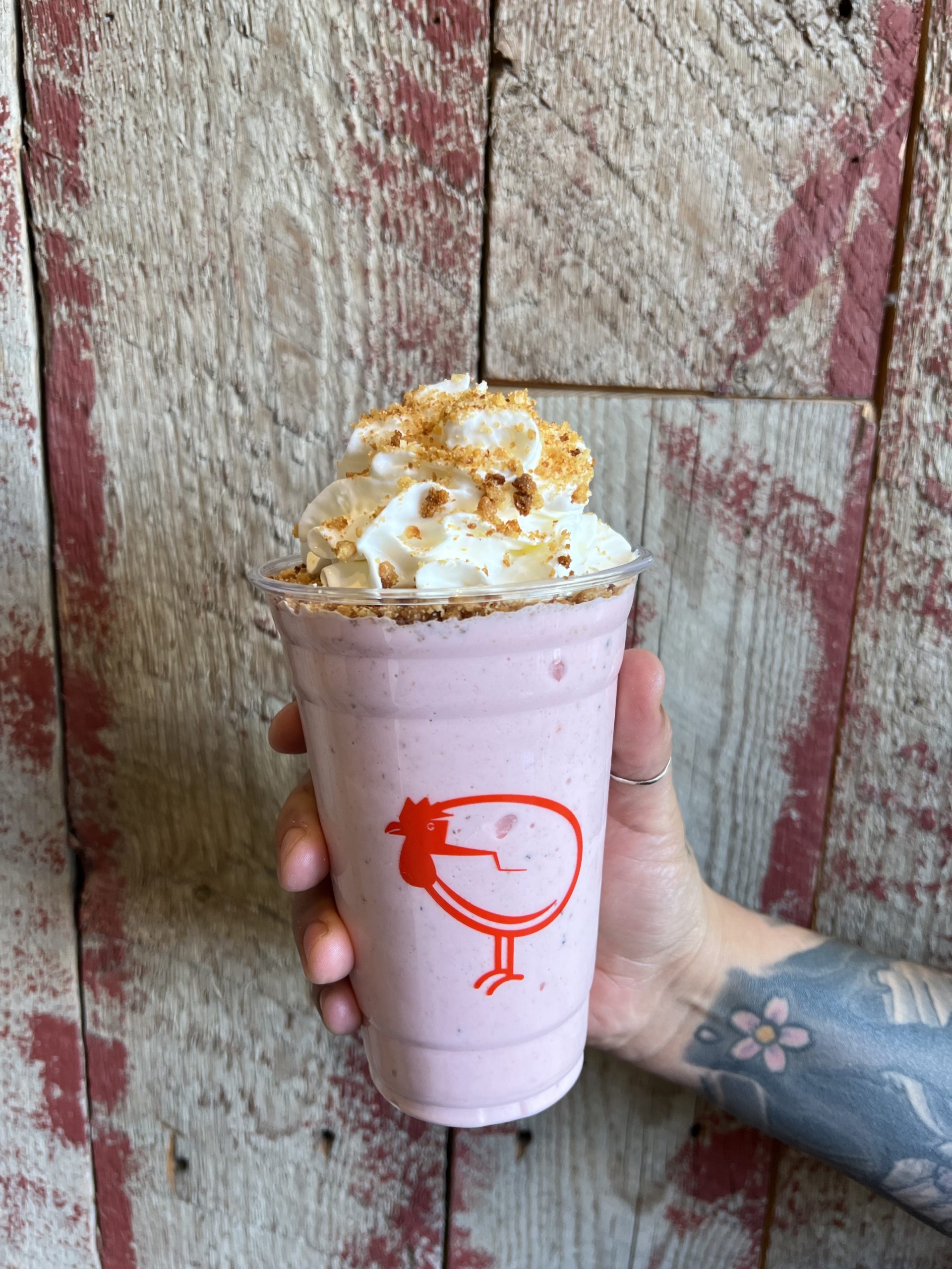 Pink milkshake being held in front of a wall