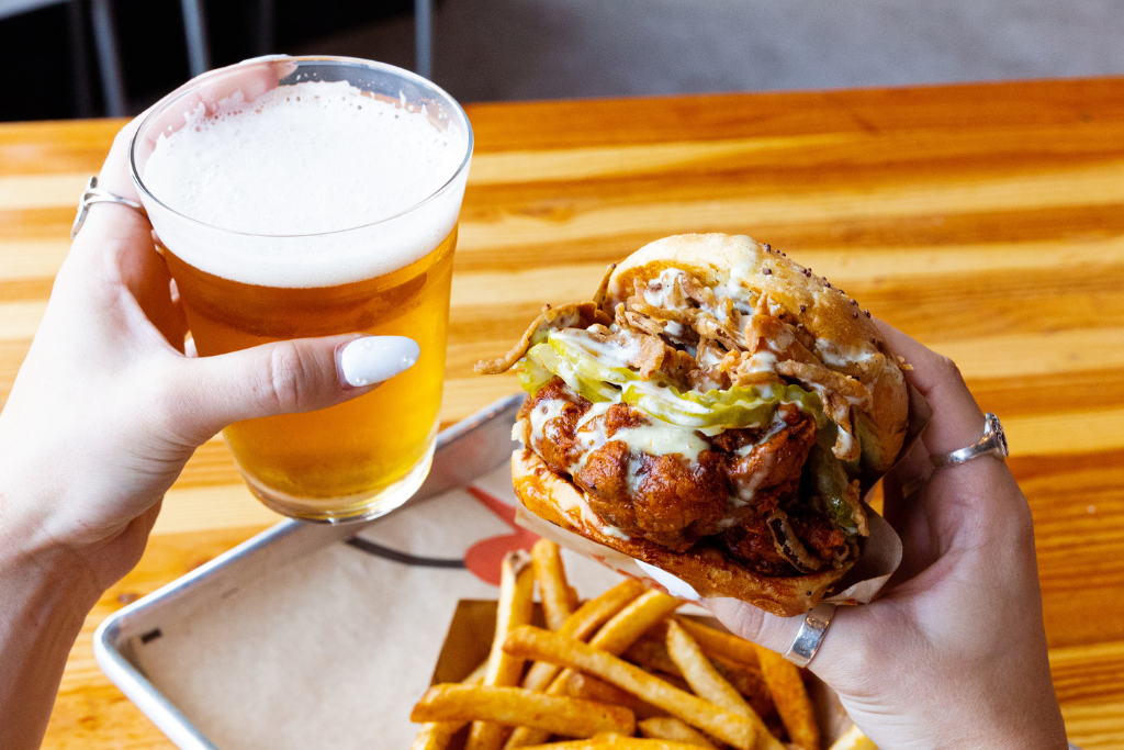 Person holding a beer and sandwich