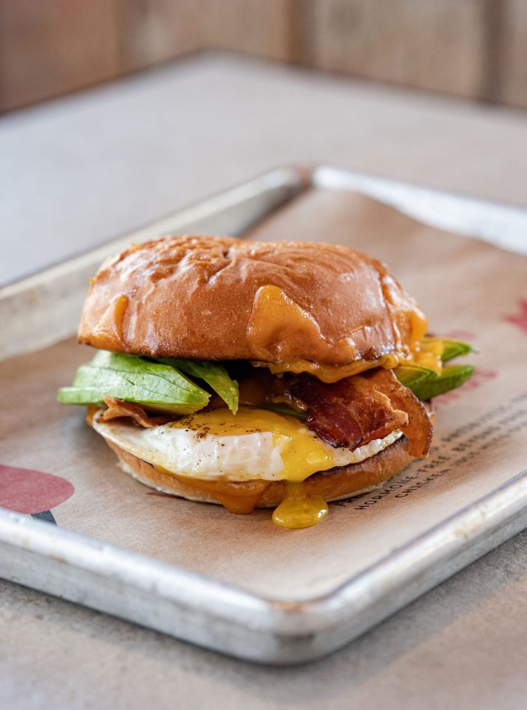 Breakfast sandwich with egg, avocado, and bacon.