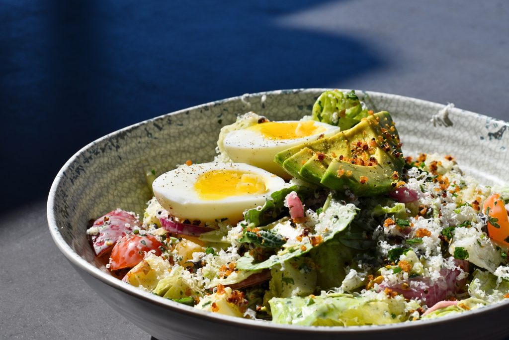 Cobb salad with avocado and soft boiled egg on top.