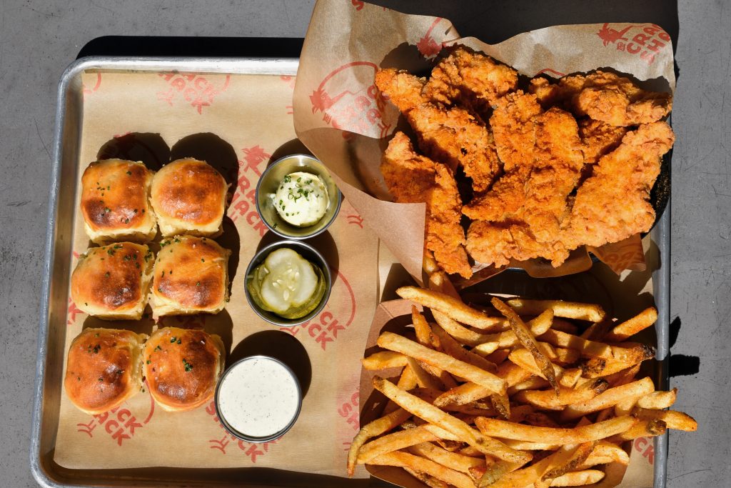 Tray with a boat of chicken tenders, a boat of fries, 6 biscuits, butter, pickles, and ranch.