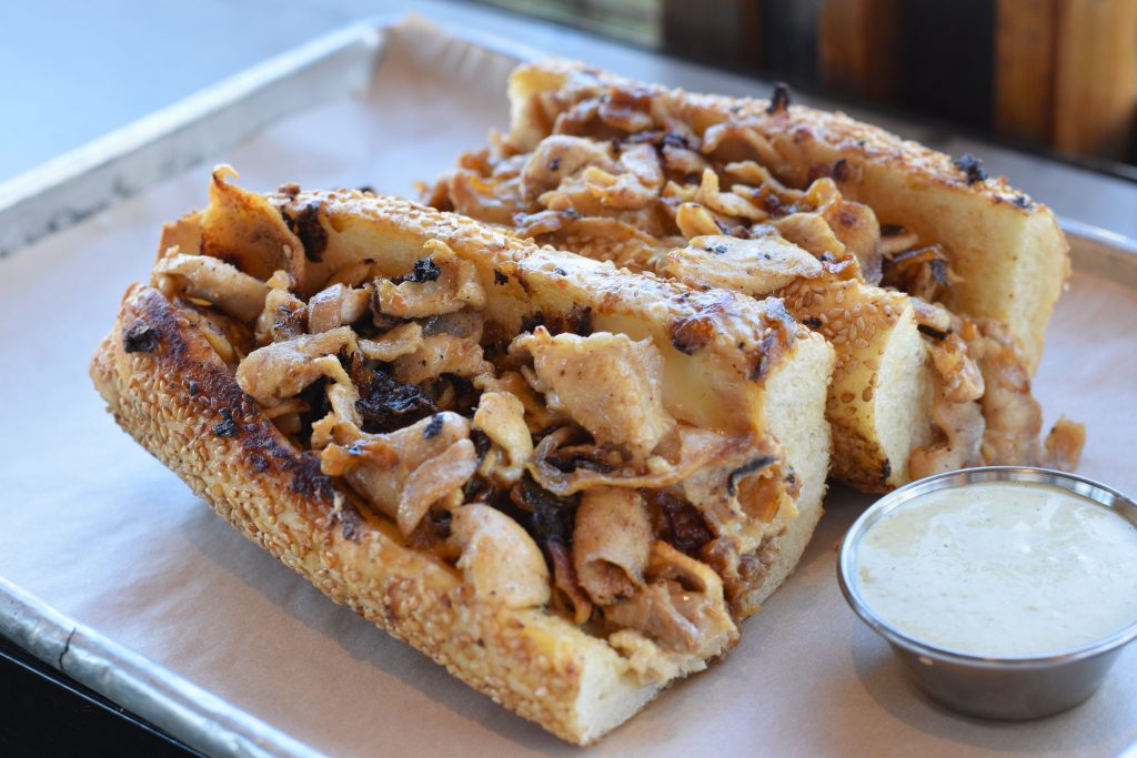 Chicken cheesesteak with sauce on a tray.