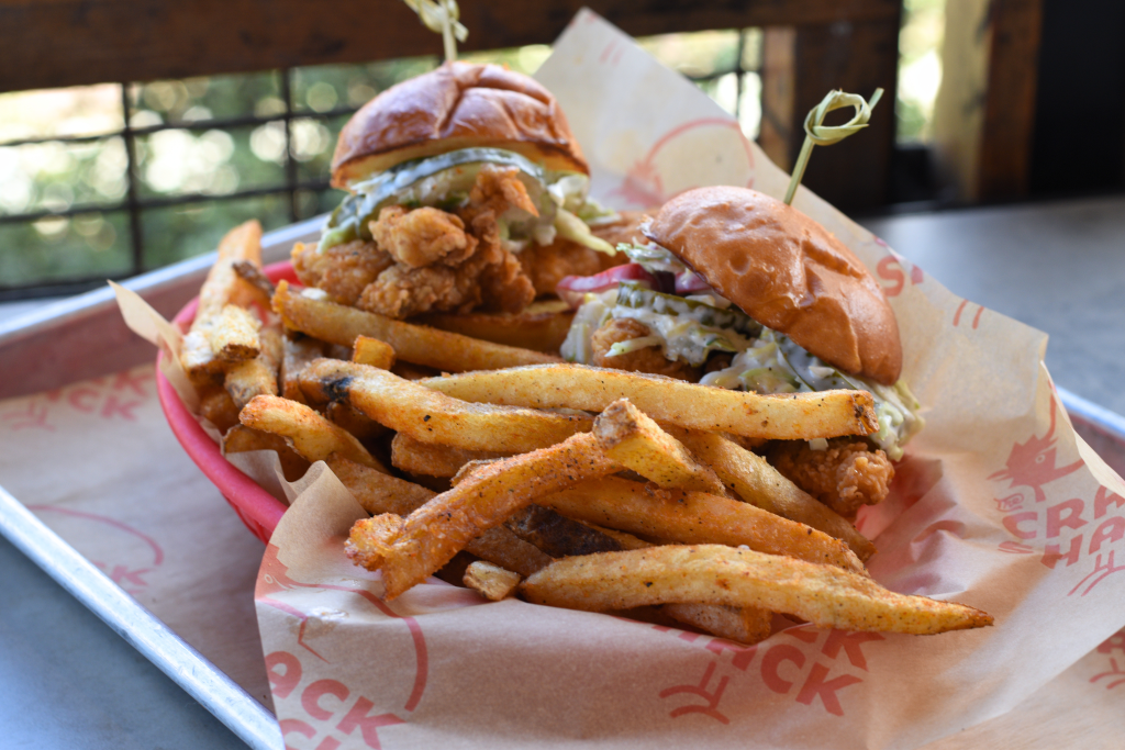 Two chicken sliders next to fries in a basket on a tray.