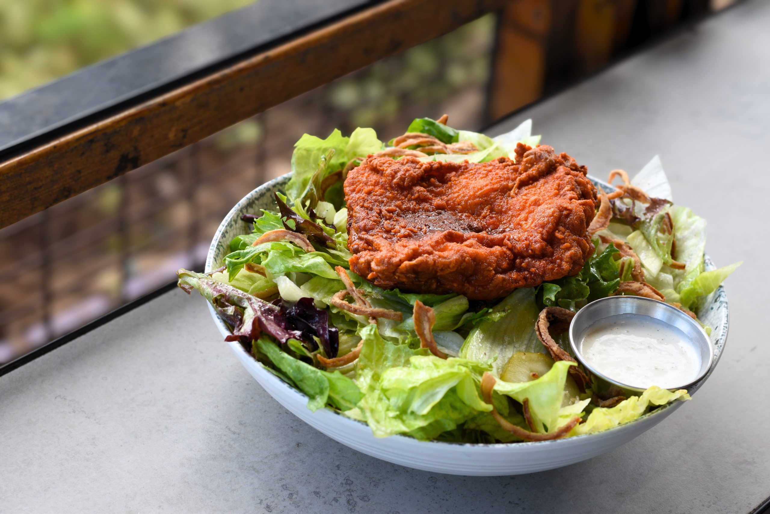Spicy fried thigh on a bed of lettuce with crispy onions and ranch.