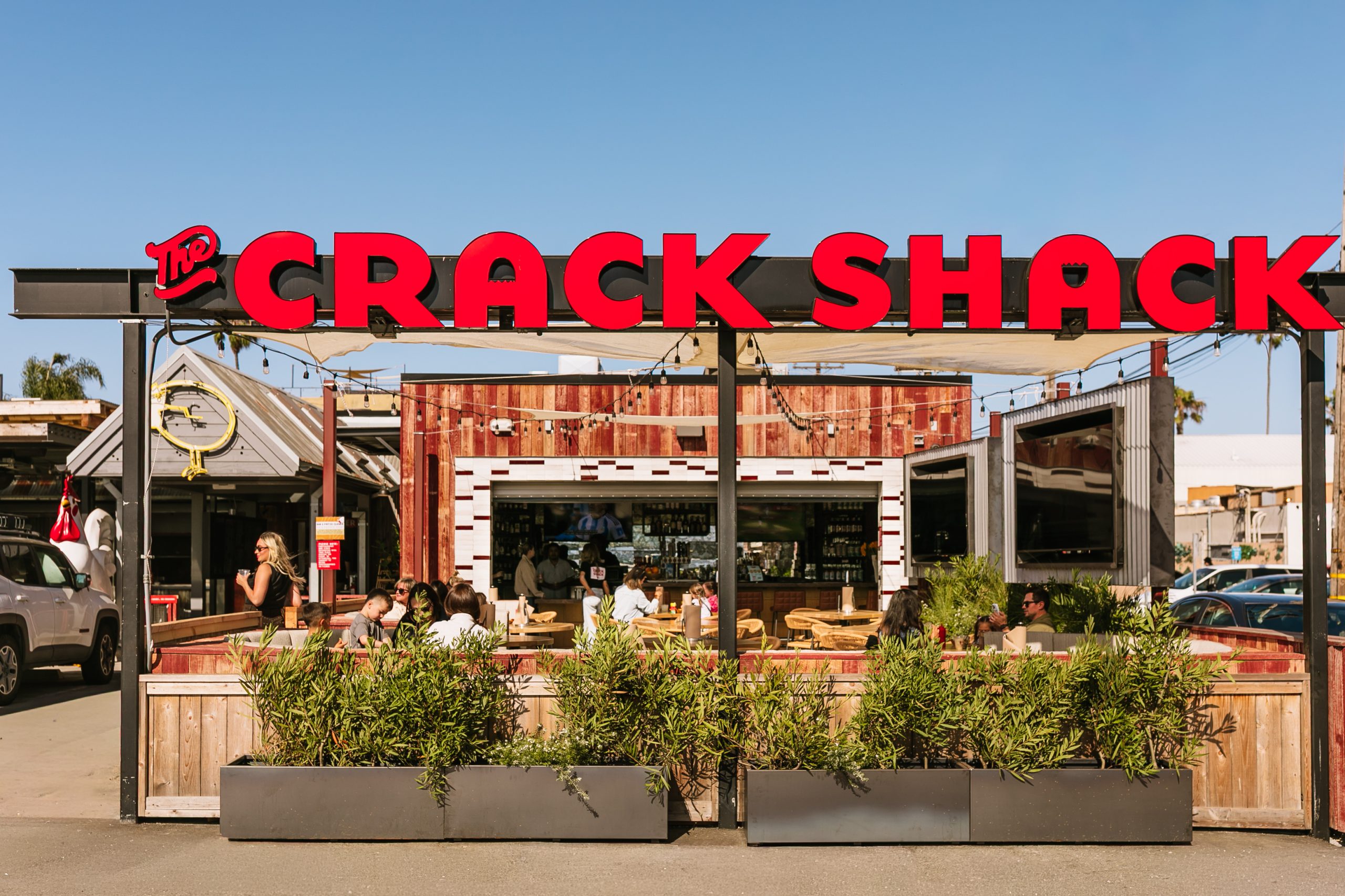 Outside shot of The Crack Shack with plants outside and people on a patio.
