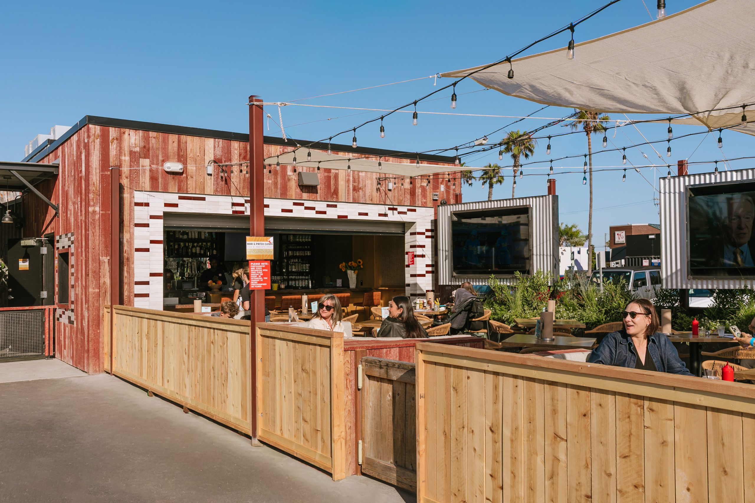 Outdoor patio with string lights and people sitting at tables.
